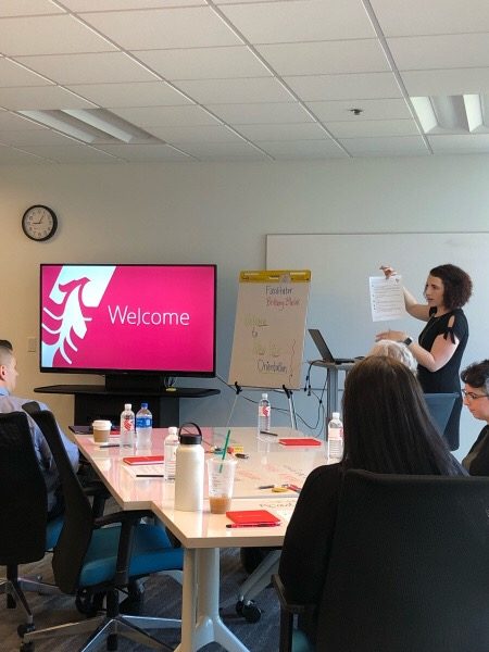 Facilitating a live session in front of a room of learners, working from a flip-chart agenda.